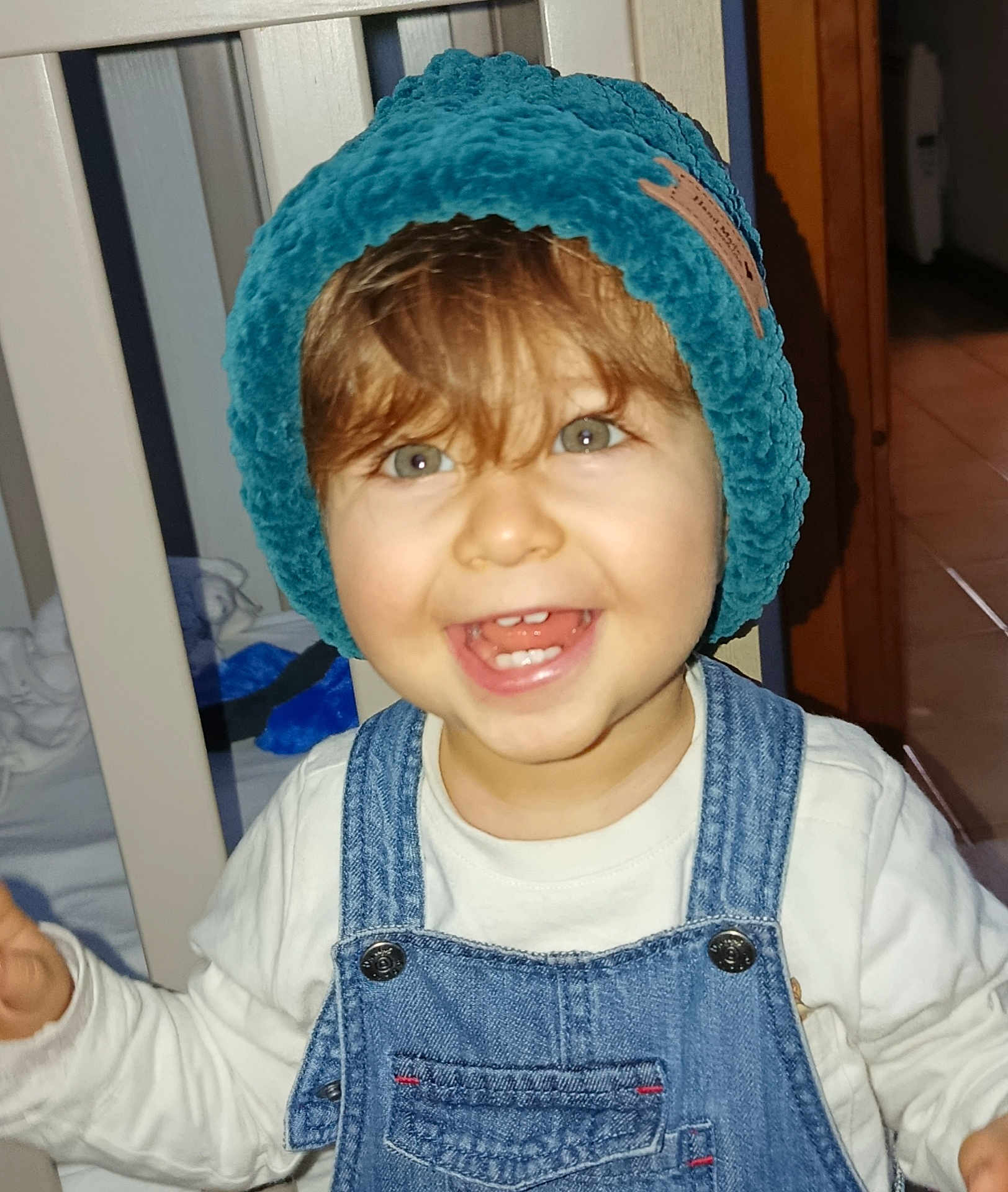 Eliott a rejoint le concours — aidez-le/la à gagner de superbes lots ! toddler, child, smiling, hat, denim_overalls, happy, indoor, face, person, baby, clothing, headwear, cute, portrait, young_child, home, furniture, light, expression, joy