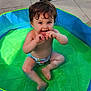 toddler, child, pool, water, sitting, playful, wet_hair, summer, outdoor, sunlight, green, blue, skin, barefoot, diaper, happy, cute, baby, fun, splash