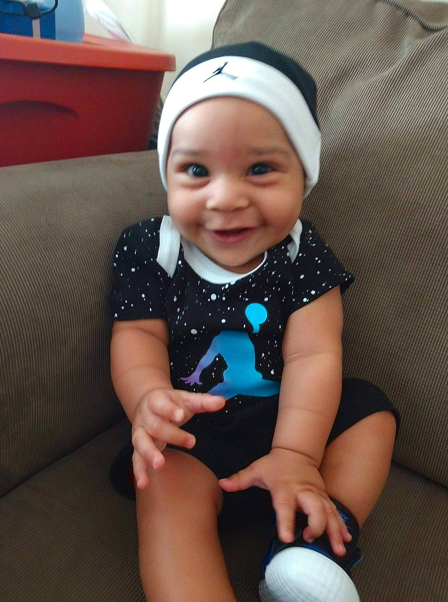 Ky is registered to the contest to win money with this photo: baby, baby_products, baby_toddler_clothing, child, headgear, headwear, joy, person, play, sitting, skin, smile, toddler