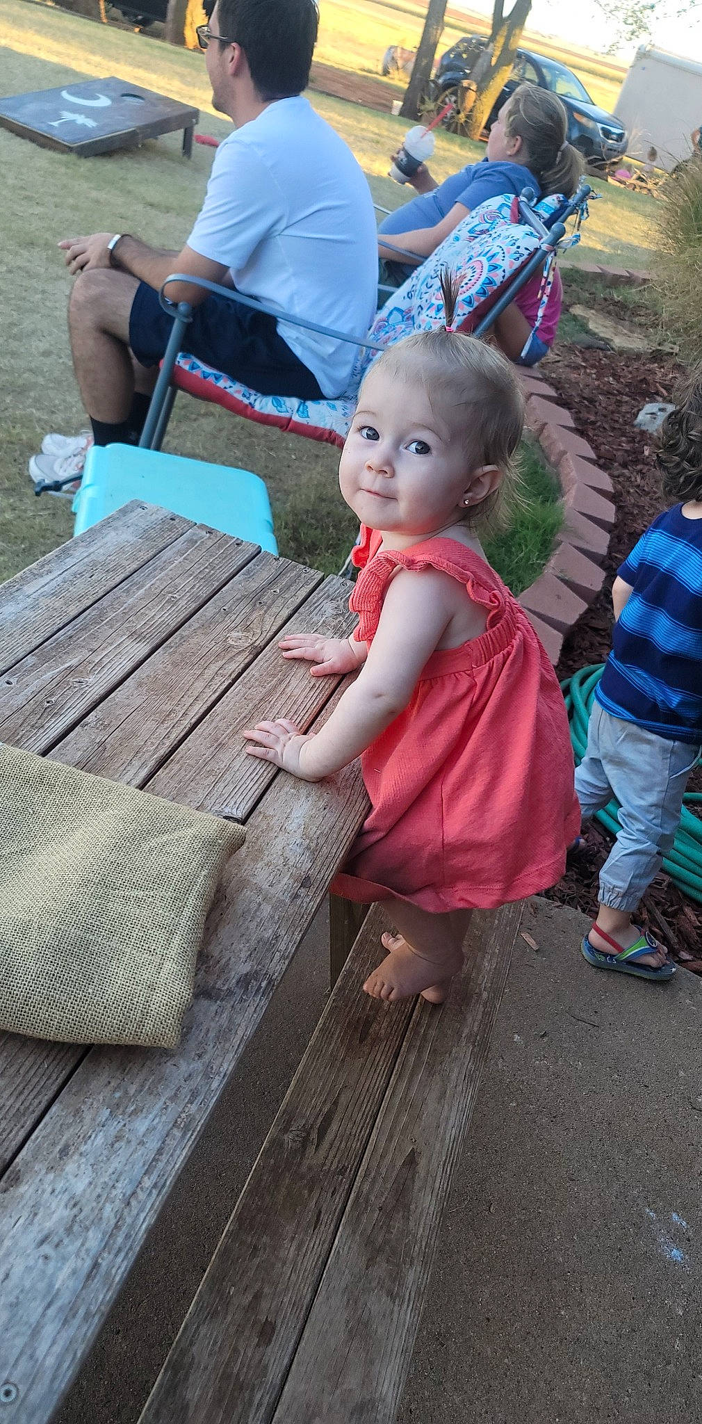 Freya joined the competition — help win amazing prizes! child, deck, flooring, fun, grass, green, hardwood, hat, leisure, outdoor_furniture, outdoor_table, person, plank, recreation, sandal, sitting, sun_hat, toddler, vacation, wood