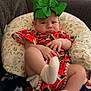 Kaylee is registered to the contest to win money with this photo: baby, child, green_bow, watermelon_dress, socks, cushion, sofa, blanket, indoor, expression, face, person, clothing, cute, infant, home, furniture, patterned, colorful, portrait