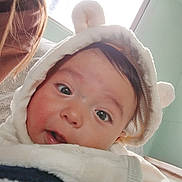 Wayne is registered to the contest to win money with this photo: baby, child, clothing, curious, cute, ears, expression, eyes, face, fluffy, hair, hood, indoor, light, mouth, person, portrait, skin, white, window