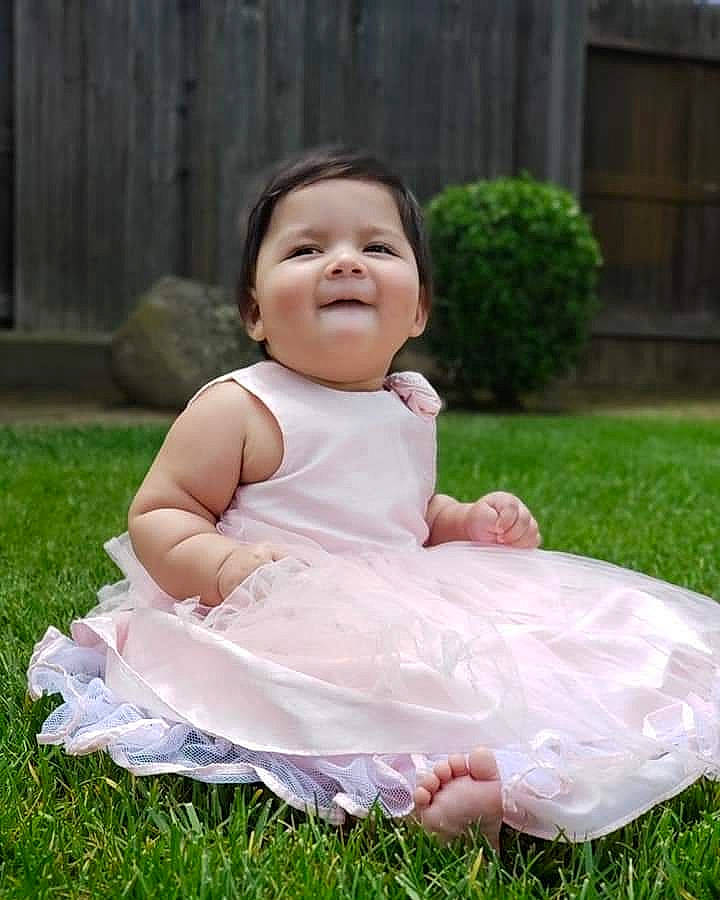 Aria is registered to the contest to win money with this photo: baby, baby_toddler_clothing, child, costume, dress, grass, happy, person, photograph, photography, pink, plant, sitting, skin, smile, toddler