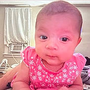 Lyrica is registered to the contest to win money with this photo: baby, infant, pink_dress, floral_pattern, face, eyes, indoor, bed, blanket, plush_toy, air_conditioner, curtains, person, child, cute, expression, lying_down, room, flower_emoji, soft_lighting