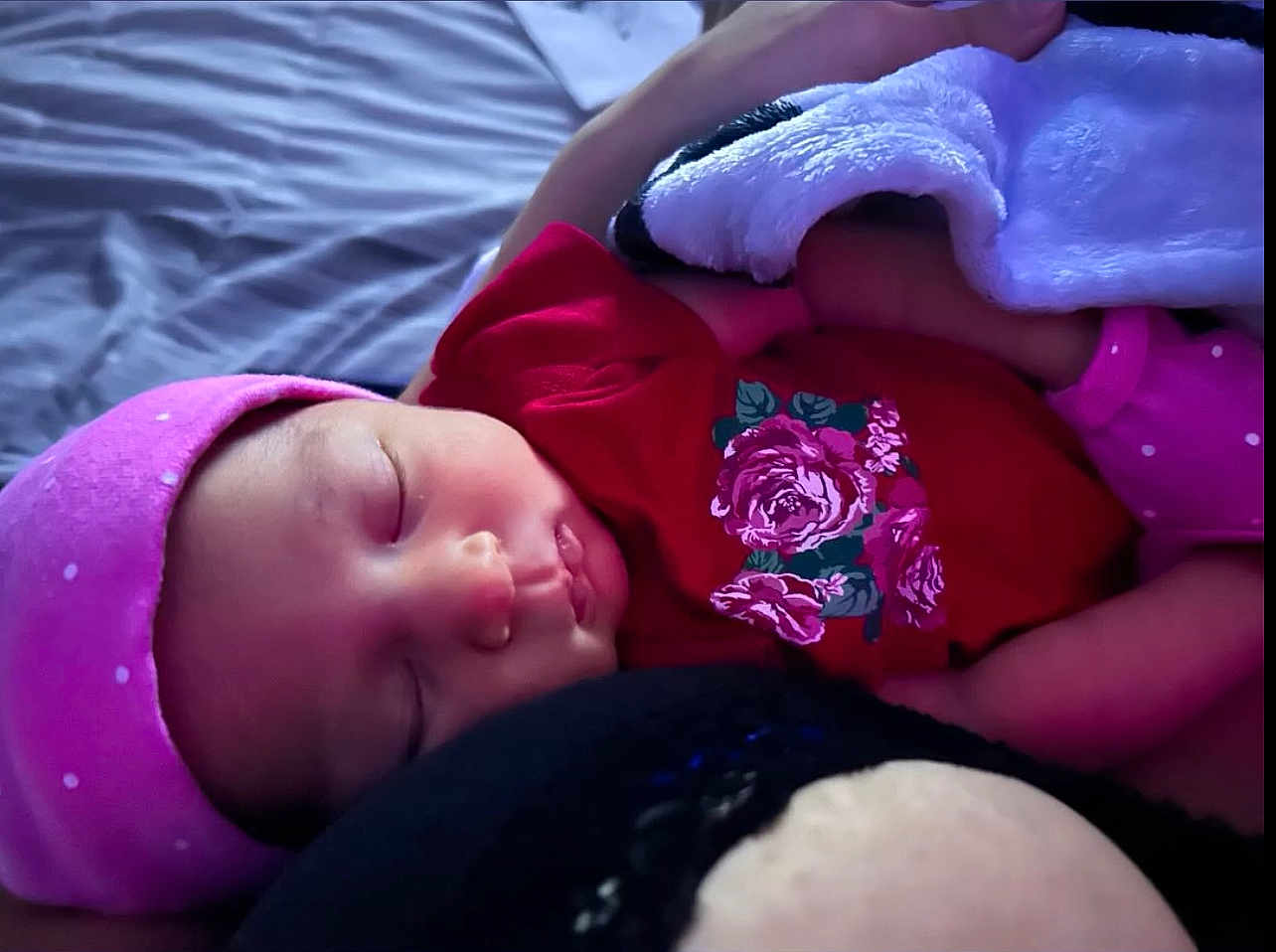 Lyrica is registered to the contest to win money with this photo: baby, sleeping, pink_hat, red_clothing, floral_pattern, blanket, soft_toy, close_up, infant, peaceful, cute, resting, bed, child, portrait, face, headwear, indoors, cozy, newborn