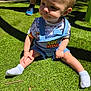 child, toddler, grass, outdoor, sunlight, toy_story, overalls, shirt, socks, baby, person, cute, shadow, nature, playing, summer, daylight, expression, sitting, footwear