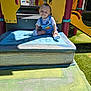 Asher joined the competition — help win amazing prizes! baby, child, playground, toy_story, overalls, outdoor, sunlight, smile, play_equipment, slide, grass, plastic, colorful, young_child, socks, person, happy, summer, park, fun