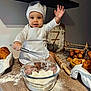 baby, child, chef_hat, whisk, flour, baking, kitchen, croissants, eggs, rolling_pin, basket, apron, smiling, messy, countertop, food, cute, cooking, portrait, happy