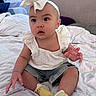 Harley is registered to the contest to win money with this photo: baby, child, infant, headband, bow, white_top, denim_shorts, yellow_socks, duck_design, bed, blanket, indoor, cute, curious, sitting, hand, face, eyes, person, clothing