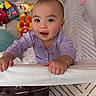 baby, child, crib, toy, purple_clothing, bracelet, face, hands, indoor, carpet, bag, playpen, curious, infant, person, smiling, bright_eyes, home, cute, young