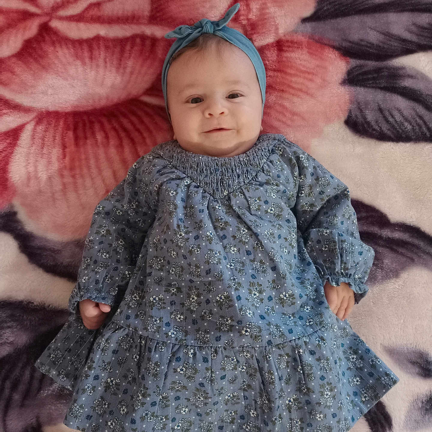 Sinda participe au concours pour gagner de l'argent avec cette photo : baby, baby_fashion, blanket, blue_dress, child, comfortable, cozy, cute, floral_pattern, happy, headband, indoors, infant, lying_down, portrait, small_hands, smiling, soft_texture, white_shoes, white_tights