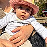 baby, child, person, hat, sunhat, drool, hand, clothing, shirt, outdoor, daylight, adult, lap, skin, face, eyes, casual, comfort, sunlight, portrait