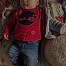 baby, child, infant, clothing, jeans, red_shirt, hooded_jacket, bedspread, floral_pattern, sock, lying_down, indoor, cute, young_child, cozy, soft_lighting, portrait, person, baby_boy, casual_wear