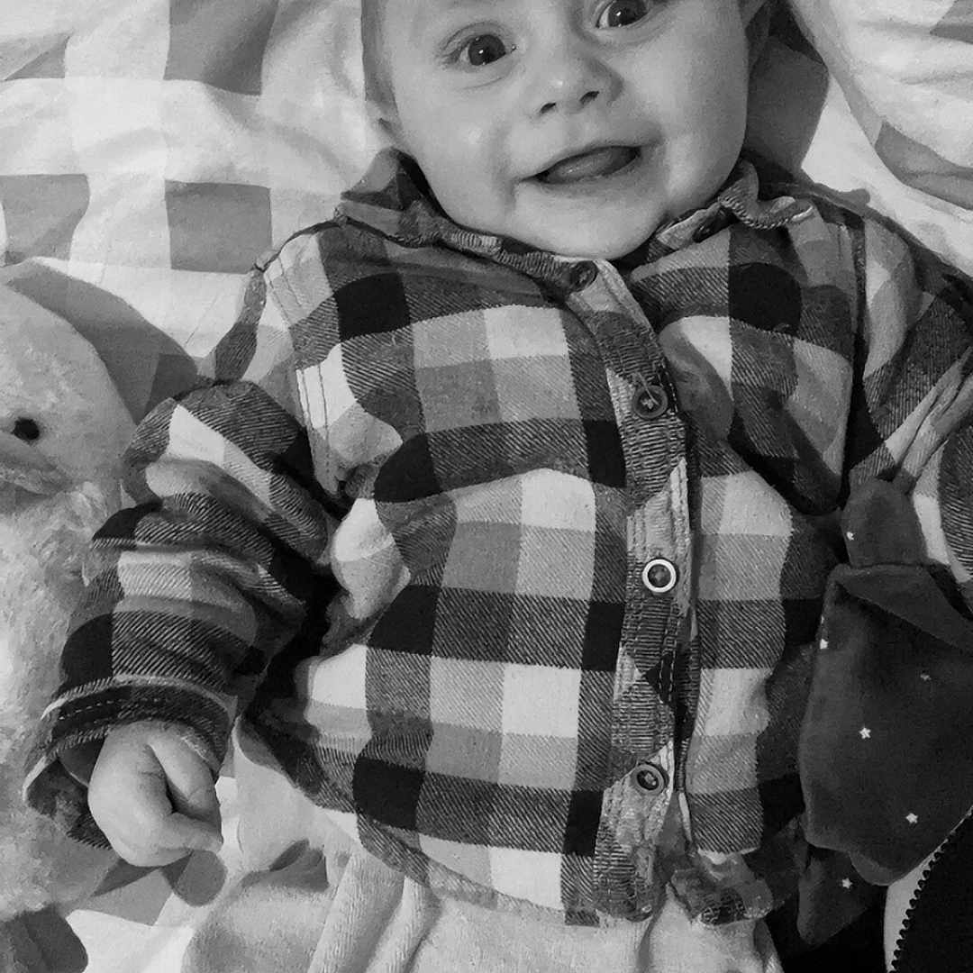 Negan participe au concours pour gagner de l'argent avec cette photo : baby, bed, bodypart, clothing, cushion, face, finger, furniture, hand, happy, head, homedecor, linen, pants, person, photography, portrait, quilt, shirt, smile