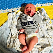 Usayd Al Malik joined the competition — help win amazing prizes! baby, infant, diaper, clothing, grey_shirt, blanket, patterned_blanket, blue, yellow, pink, cute, lying_down, hand_up, soft_texture, newborn, person, indoors, cozy, smiling, face