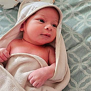 Lucas is registered to the contest to win money with this photo: newborn, baby, infant, towel, hooded_towel, bedspread, pattern, clothing, blanket, soft, skin, face, eyes, hand, sleeping_area, cozy, cute, indoors, resting, portrait