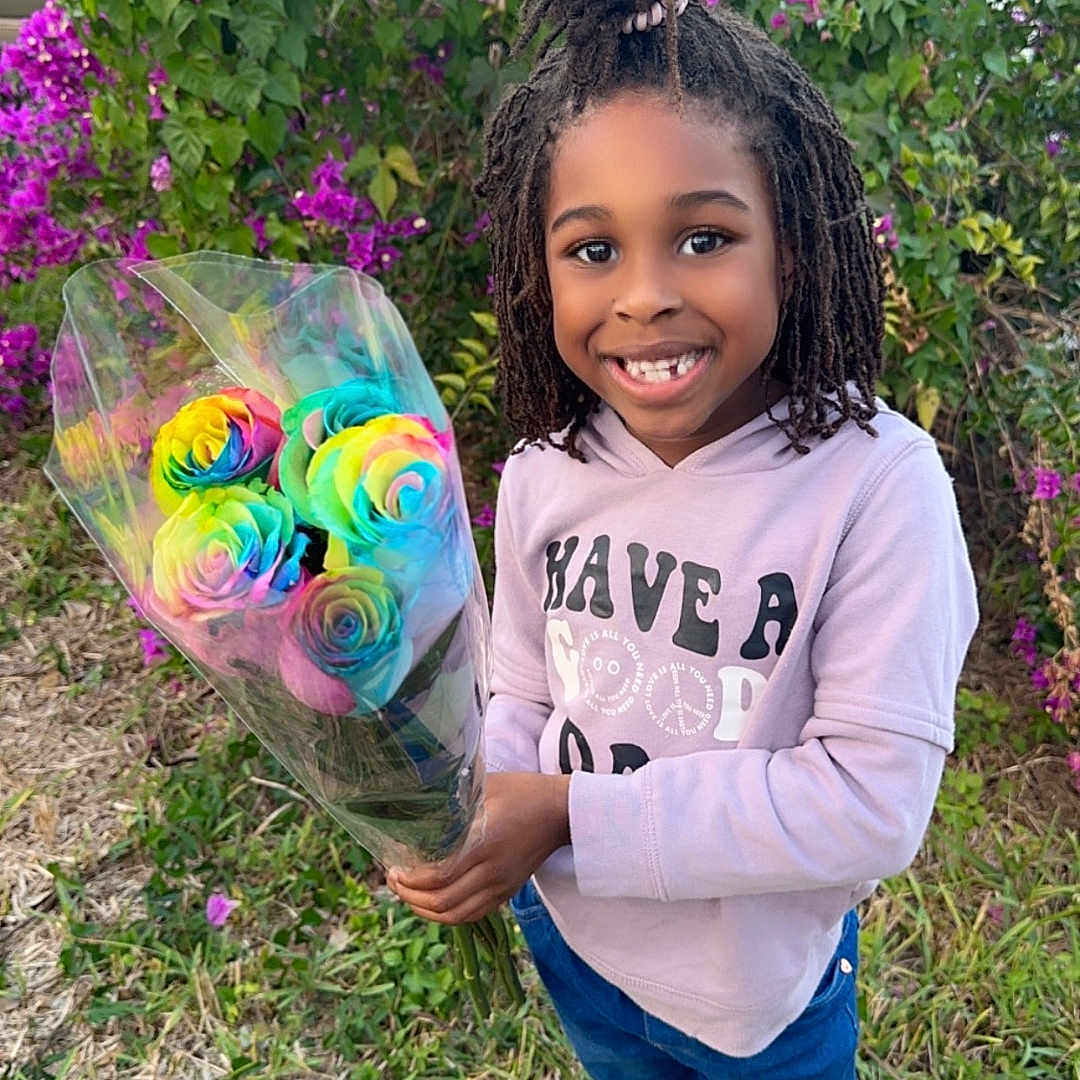 Jaurnee is registered to the contest to win money with this photo: casual_clothing, child, cute, daylight, flower_bouquet, garden, grass, greenery, happy, hoodie, jeans, nature, outdoor, person, portrait, purple_flowers, rainbow_roses, shoes, smiling, standing
