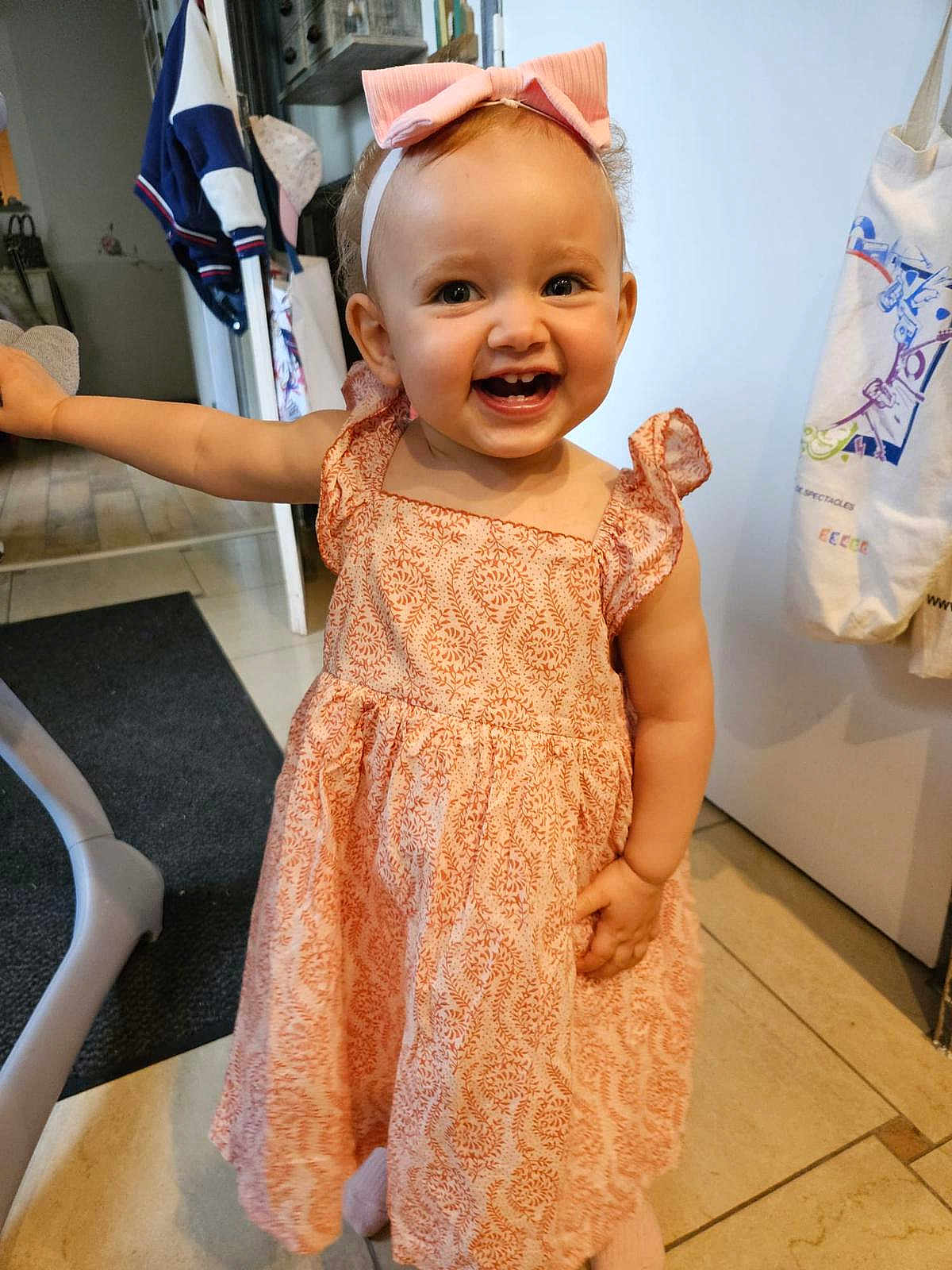 Elyne a rejoint le concours — aidez-le/la à gagner de superbes lots ! toddler, child, smiling, dress, indoor, headband, pink, happy, person, floor, furniture, hand, face, cute, clothing, pattern, standing, baby, young_child, room