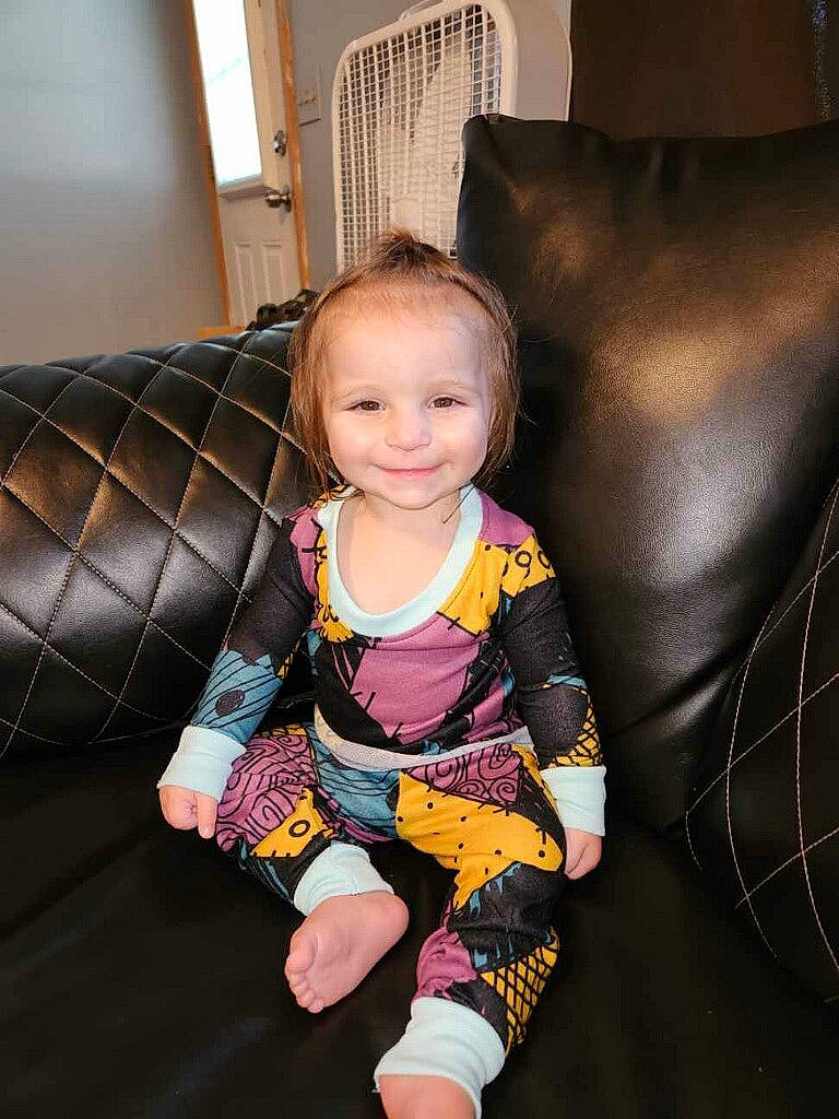 Oaklyn is registered to the contest to win money with this photo: arm, armrest, baby, baby_toddler_clothing, chair, cheek, comfort, couch, dress, eye, finger, flooring, furniture, joy, lap, leg, person, sitting, sleeve, smile