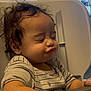 baby, child, closed_eyes, curly_hair, cute, expression, funny_face, furniture, hand, high_chair, indoor, kitchen, messy_hair, person, puckered_lips, sitting, striped_shirt, table, toddler, young_child