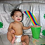 Kobi is registered to the contest to win money with this photo: baby, cereal, child, colorful, curly_hair, cute, decorations, diaper, festive, food, green_bucket, indoor, infant, playful, portrait, rainbow, shamrock, silver_fabric, sitting, smiling