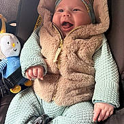 Eysmë a rejoint le concours — aidez-le/la à gagner de superbes lots ! baby, infant, smiling, happy, knitwear, fluffy_vest, headwrap, car_seat, plush_toy, bee_toy, child, cute, cozy, indoors, seatbelt, young_child, portrait, hand, clothing, warm
