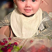 Artemis is registered to the contest to win money with this photo: baby, background, berries, bib, blond_hair, child, clothing, cute, face, food, happy, high_chair, indoor, infant, person, portrait, sitting, smiling, table, young_child
