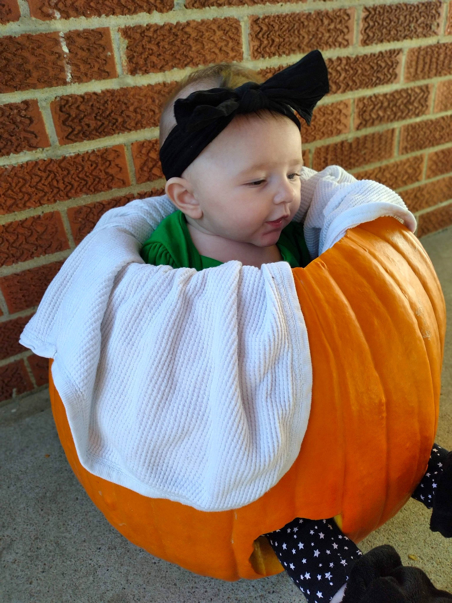 Amara is registered to the contest to win money with this photo: baby, baby_toddler_clothing, brick, brickwork, calabaza, child, comfort, cucurbita, fun, grass, happy, human_body, orange, outerwear, pattern, person, plant, pumpkin, sitting, squash