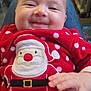 baby, infant, smiling, face, cheeks, christmas_outfit, santa_motif, red_clothing, polka_dot, onesie, hand, closeup, portrait, cute, indoor, fabric, soft_texture, happy, young_child, seated