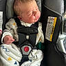 newborn, baby, car_seat, infant, sleeping, onesie, clothing, safety_harness, red_button, cushion, strap, child, face, hand, cozy, patterned, indoors, cute, resting, transportation