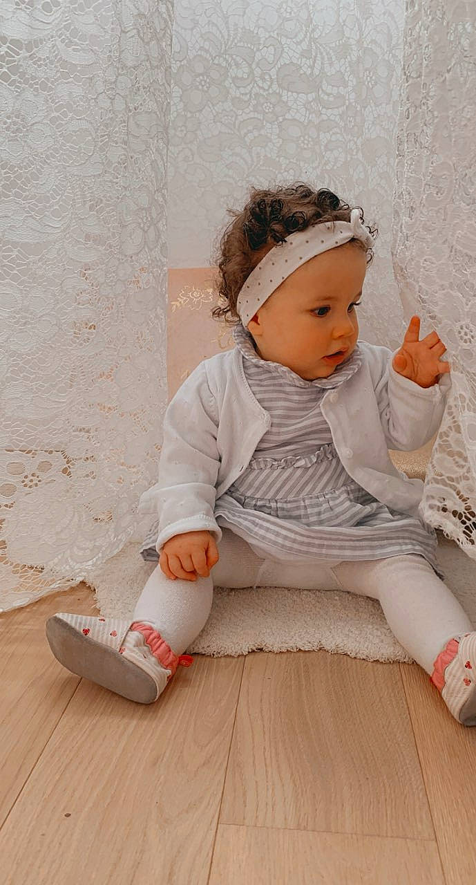 Léna a rejoint le concours — aidez-le/la à gagner de superbes lots ! baby, baby_toddler_clothing, barefoot, cap, comfort, floor, flooring, foot, happy, hardwood, headband, headpiece, headwear, human_leg, outerwear, person, sitting, skin, sleeve, standing
