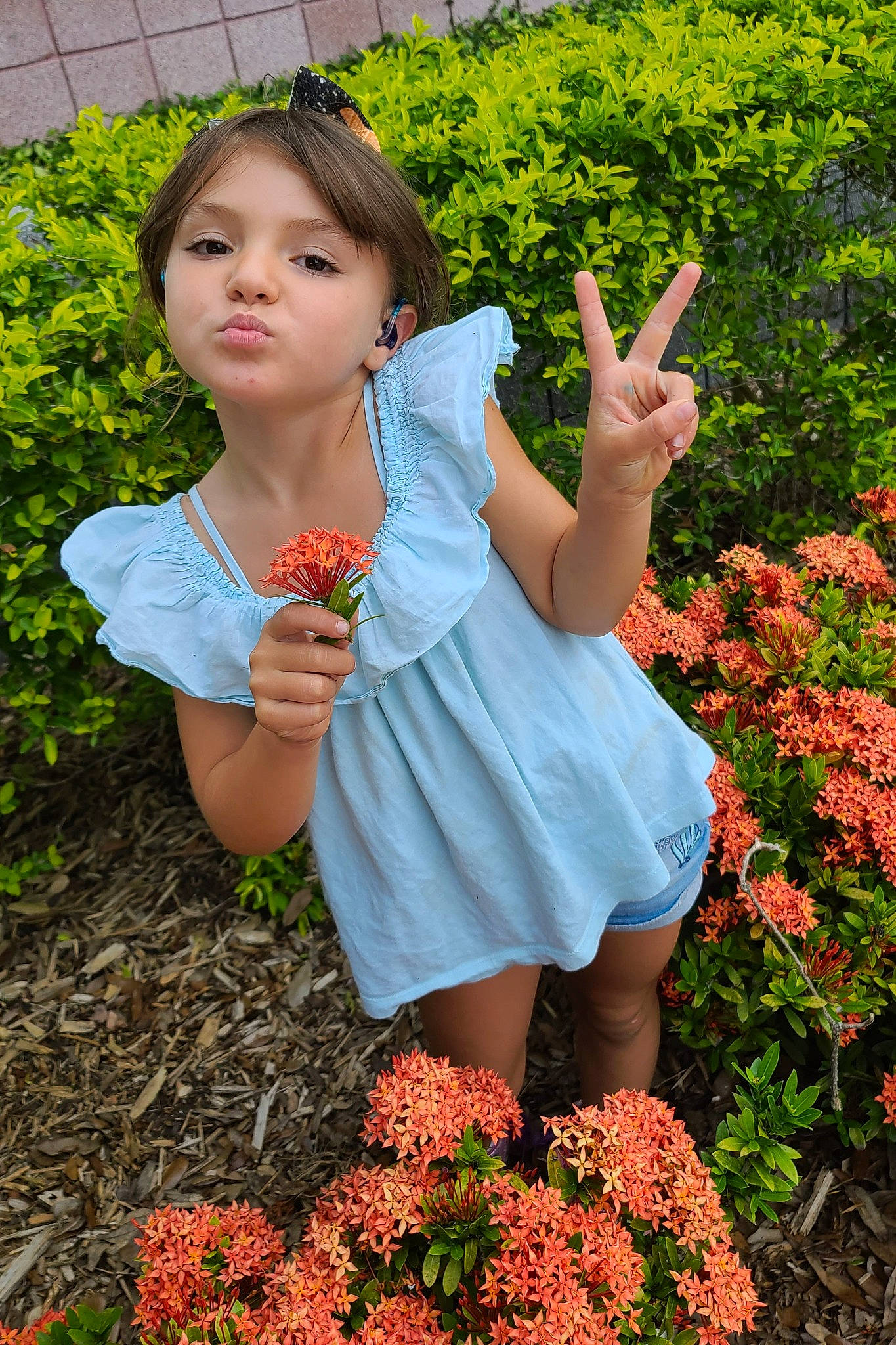 Skye is registered to the contest to win money with this photo: botany, dress, face, flower, flowering_plant, gesture, grass, groundcover, hand, happy, leaf, nature, orange, people_in_nature, person, petal, pink, plant, red, summer