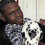 person, dog, dalmatian, indoor, portrait, black_and_white, face, couch, casual, relaxed, young_adult, hairstyle, patterned_clothing, comfort, pet, animal, friendship, close_up, affection, home