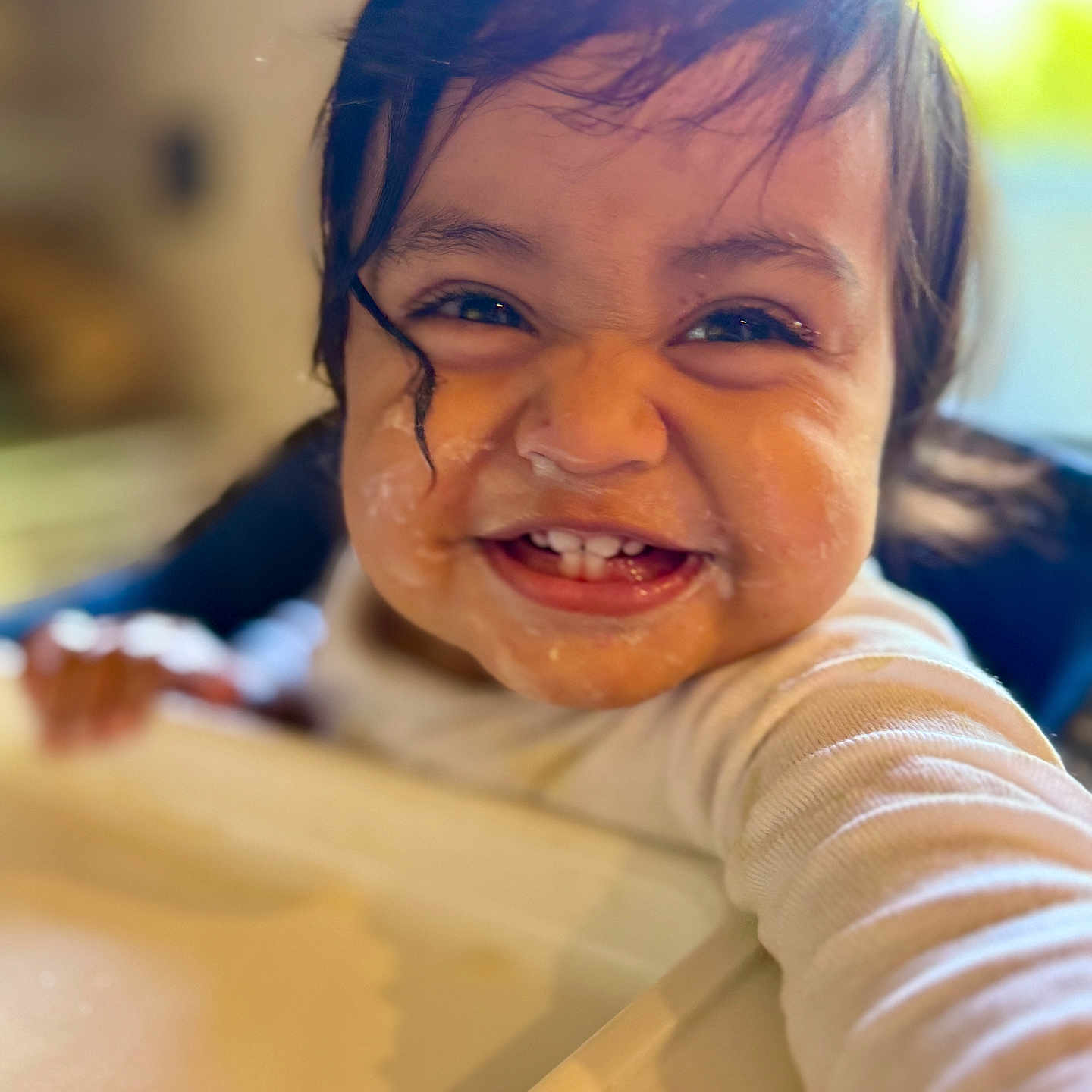 Agastya is registered to the contest to win money with this photo: baby, child, infant, smiling, happy, portrait, close_up, face, teeth, dark_hair, brown_eyes, indoor, warm_lighting, sitting, reaching, clothing, long_sleeves, white_shirt, candid, family_photo