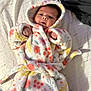 Layla is registered to the contest to win money with this photo: baby, infant, robe, floral_pattern, bed, blanket, sleepwear, cute, soft_texture, child, face, hands, hood, colorful, lying_down, indoors, cozy, warm, person, portrait