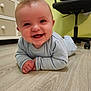 baby, child, smiling, pajamas, floor, wooden_floor, indoor, furniture, drawer, office_chair, happy, person, crawling, cute, head, hands, room, light, expression, portrait
