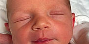 Layla is registered to the contest to win money with this photo: baby, newborn, sleeping, infant, face, skin, blanket, hand, peaceful, closeup, portrait, soft_light, cozy, white_clothing, indoors, cute, rest, head, human, child