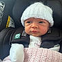 Layla is registered to the contest to win money with this photo: baby, infant, car_seat, white_hat, pink_blanket, clothing, face, child, newborn, cute, portrait, seatbelt, child_safety, warm, knit, soft, indoor, person, looking, wrapped