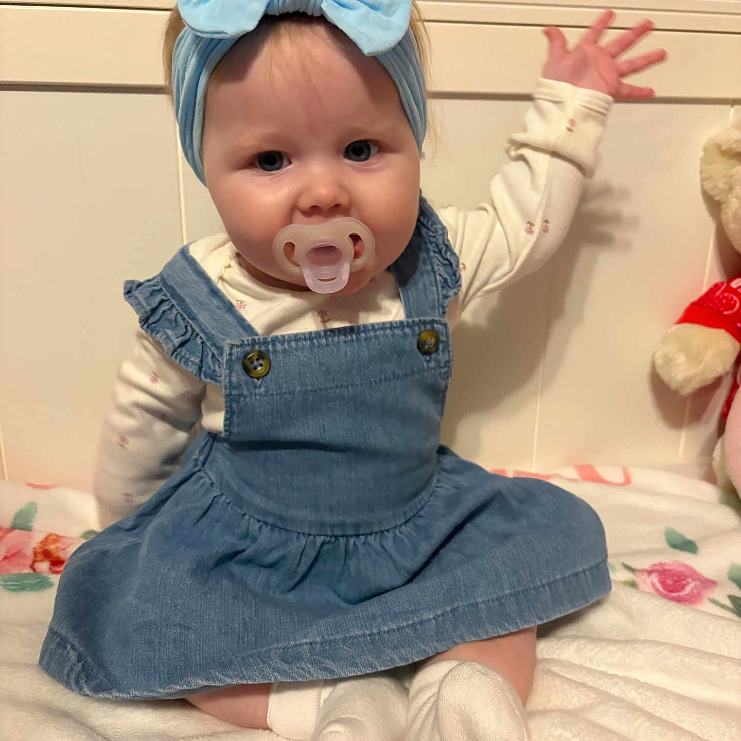 Aaliyah joined the competition — help win amazing prizes! baby, child, infant, sitting, portrait, indoors, bed, blanket, blue_dress, denim, bow, headband, pacifier, socks, stuffed_animal, raised_hand, smiling, face, nursery, close_up