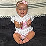 baby, child, smiling, clapping, sitting, headband, bow, white_shirt, pink_clothing, barefoot, couch, blanket, indoor, happy, cute, infant, portrait, person, furniture, home