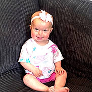 Lottie is registered to the contest to win money with this photo: baby, child, smile, headband, bow, tshirt, nike, pink, shorts, sitting, couch, furniture, indoors, happy, cute, person, skin, foot, hand, face