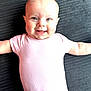 Lottie is registered to the contest to win money with this photo: baby, infant, smiling, pink_onesie, lying_down, happy, face, arms_outstretched, closeup, child, cute, skin, head, eyes, mouth, person, human, indoors, texture, background