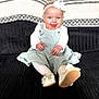 baby, child, smiling, sitting, headband, dress, white_shoes, bow, tights, couch, black_couch, corduroy, happy, infant, indoors, cute, portrait, person, fashion, joyful