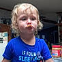 Jackson is registered to the contest to win money with this photo: toddler, child, blue_shirt, curly_hair, peanut_butter, kitchen, snack, food, indoor, person, cute, expression, tongue, funny, young_child, blonde, clothing, holding, standing, jar