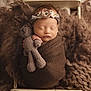 newborn, baby, sleeping, wrapped, brown, blanket, crocheted_toy, teddy_bear, headband, flower, cute, peaceful, soft_texture, knit, wooden_cradle, portrait, infant, cozy, child, indoor