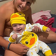 Elyo a rejoint le concours — aidez-le/la à gagner de superbes lots ! baby, bed, blanket, child, clothing, cute, duck_outfit, face, family, foot, hand, happy, head, indoor, person, portrait, sitting, skin, smiling, yellow_hat