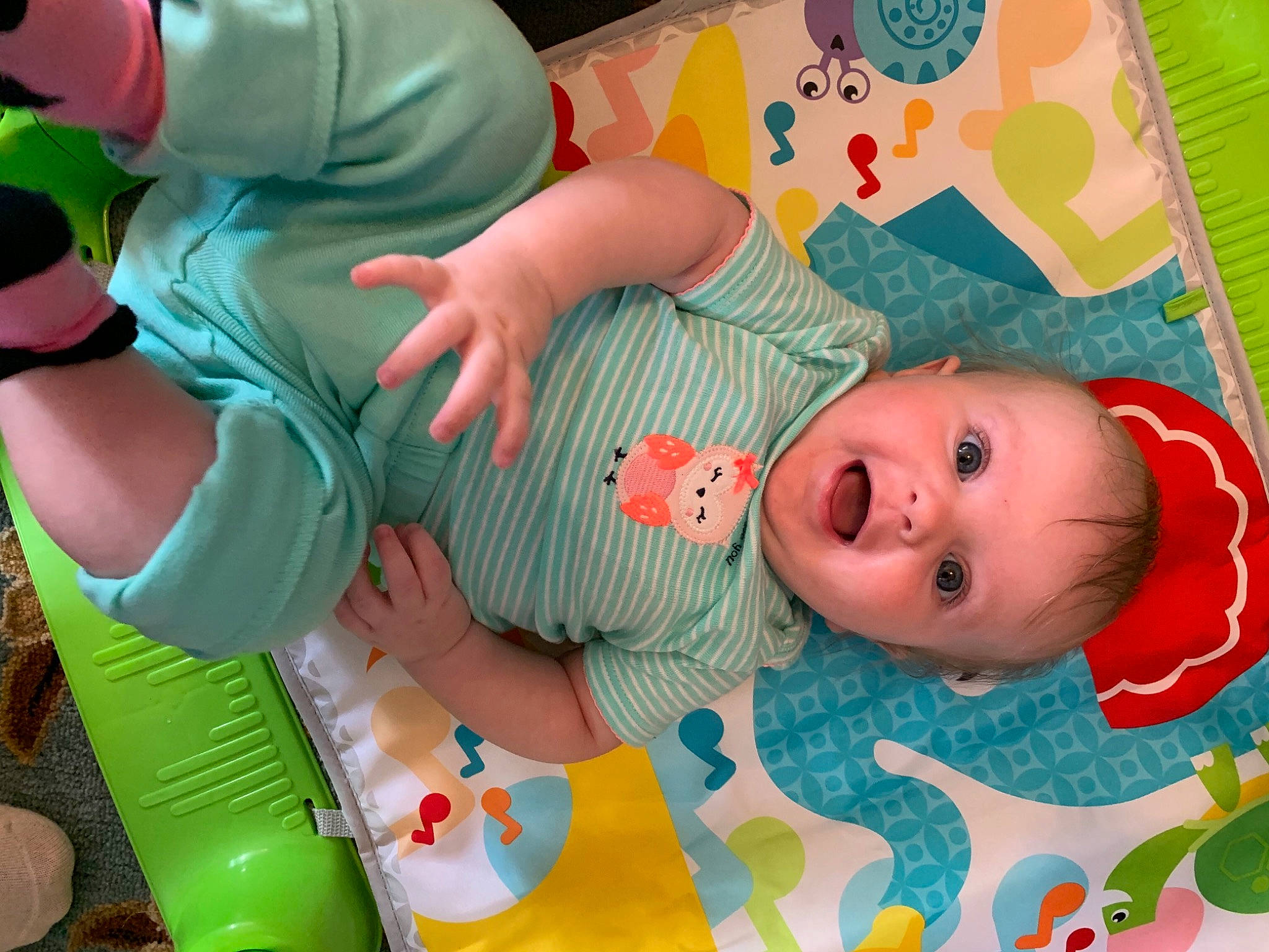 Elle is registered to the contest to win money with this photo: baby, baby_products, baby_toddler_clothing, baby_toys, cheek, child, fun, green, leisure, linens, mouth, pattern, person, pink, playmat, room, skin, textile, toddler, toy