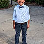 black_shoes, bow_tie, boy, bushes, casual, child, concrete, fashion, fence, greenery, happy, jeans, outdoor, person, portrait, sidewalk, smiling, standing, white_shirt, young