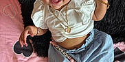 Xareni joined the competition — help win amazing prizes! baby, smiling, girl, white_top, blue_skirt, headband, gold_jewelry, bracelet, necklace, earrings, pink_bedspread, heart_pattern, black_pillow, lying_down, happy, cute, infant, person, child, indoors