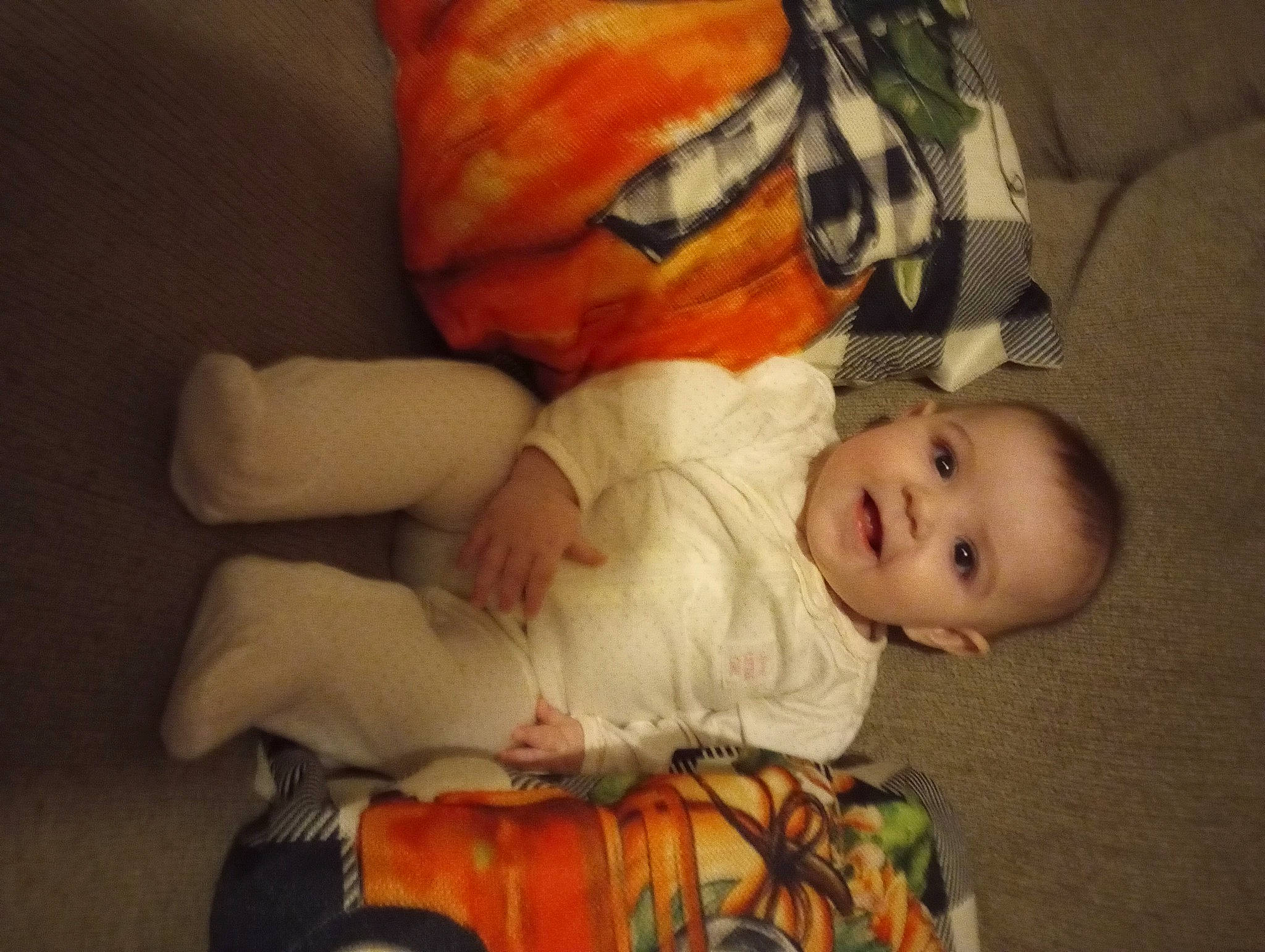 Eryana is registered to the contest to win money with this photo: baby, baby_toddler_clothing, bedtime, carmine, cheek, child, comfort, flooring, fun, head, lap, linens, mouth, nose, orange, person, room, sitting, smile, toddler